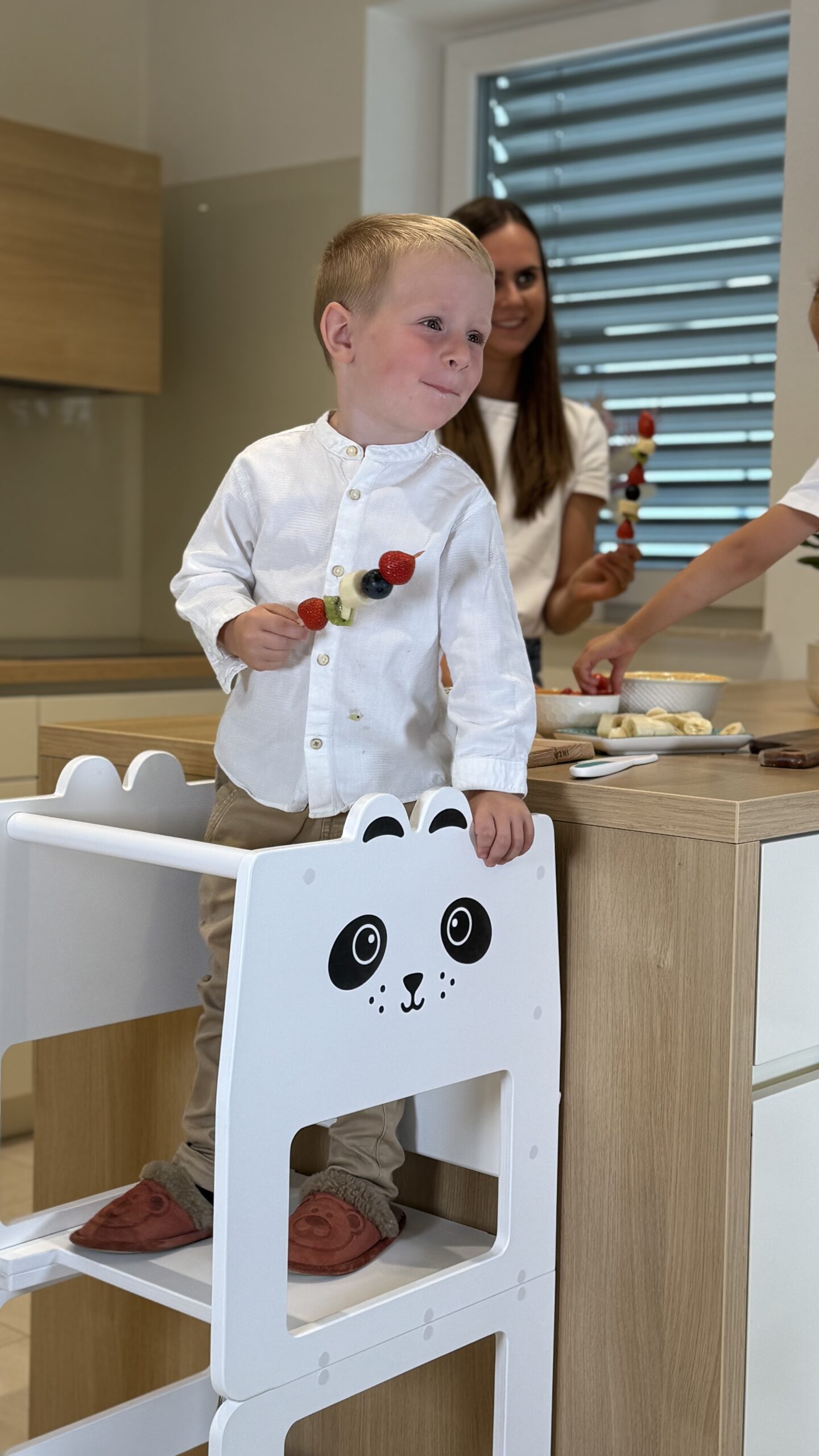 Otrok uporablja pomagalček v kuhinji pri pripravi hrane po Montessori pristopu.